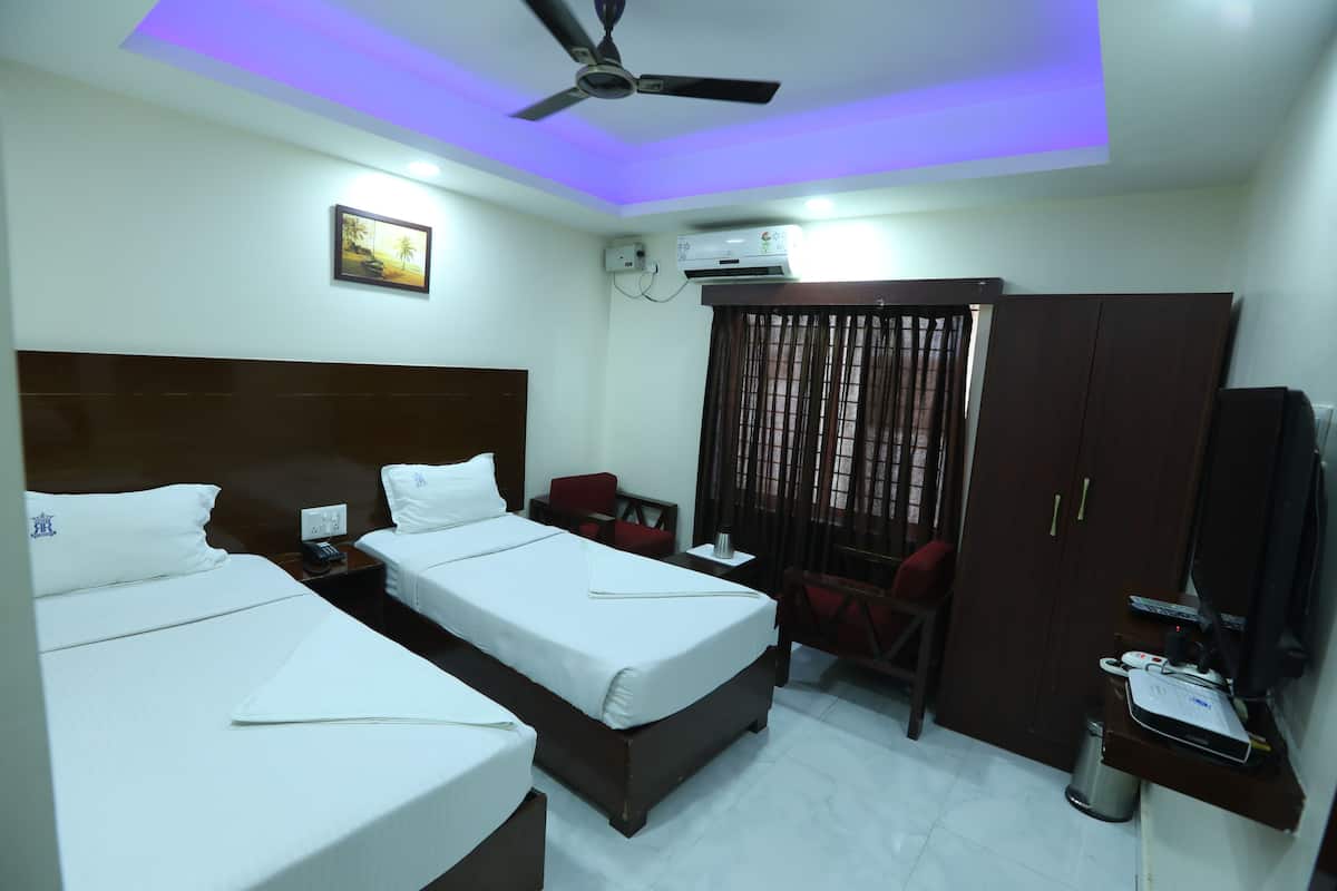 A hotel room with two beds, a ceiling fan, an air conditioning unit, a TV, and a desk with a computer.