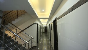A modern hotel hallway with a staircase, a ceiling with recessed lighting, and a polished floor. - Hotel RR International (Bengaluru)