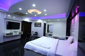 Una habitación de hotel moderna con una cama grande, un televisor de pantalla plana, un escritorio y una silla.