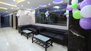 A modern lobby with black leather sofas, a glass coffee table, and a marble column. - Hotel RR International (Bengaluru)