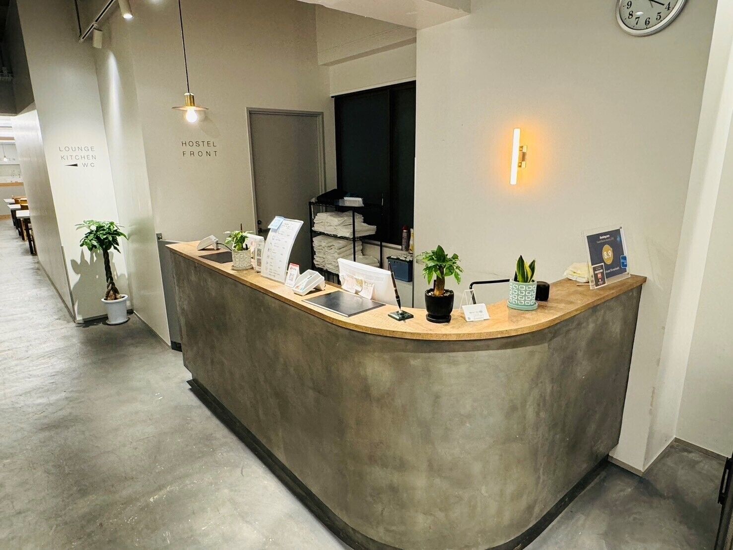 A reception desk with a clock, a lounge sign, and a sign for the hostel front.
