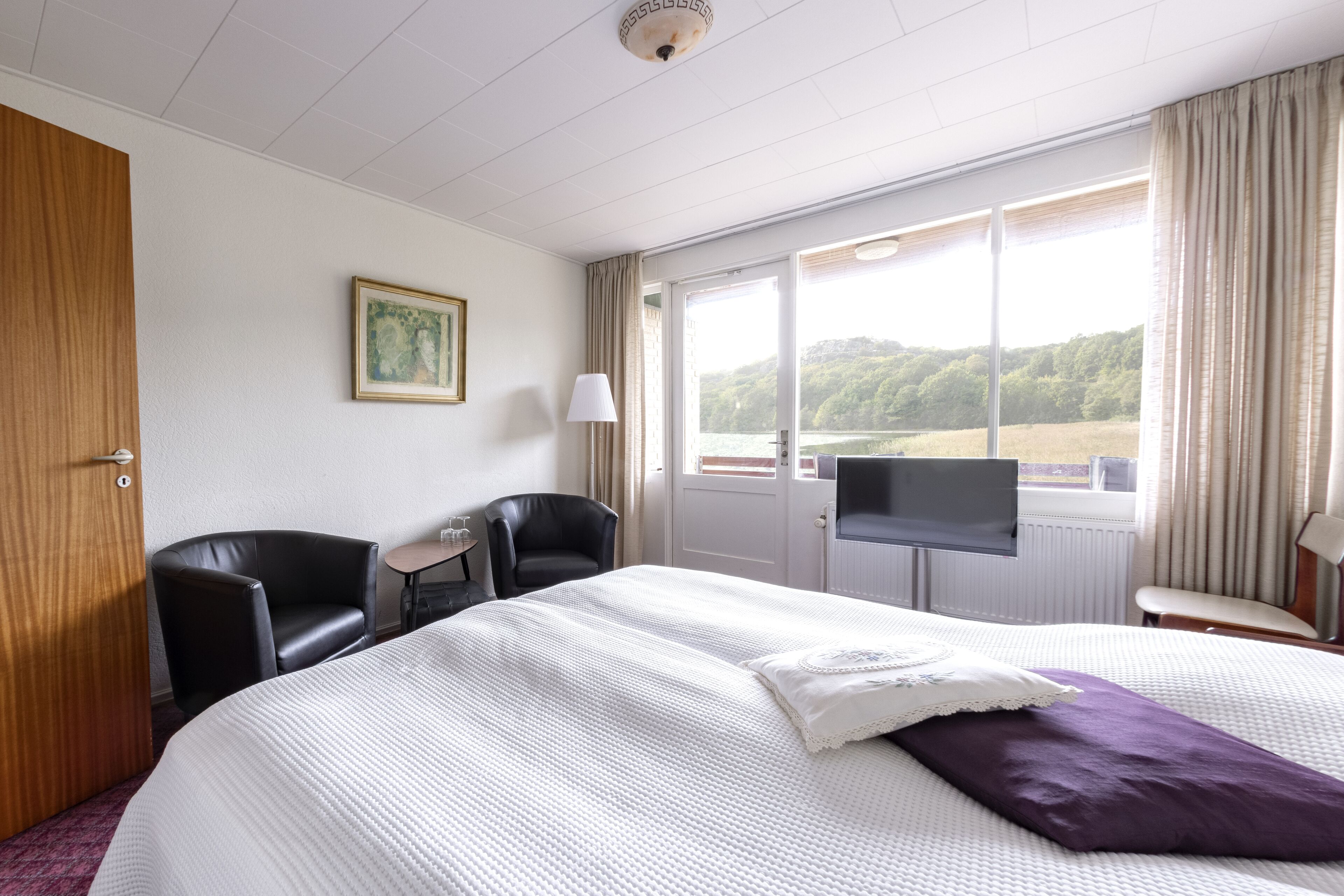 Une chambre d’hôtel avec un grand lit, une télévision, un bureau et une fenêtre donnant sur la campagne.