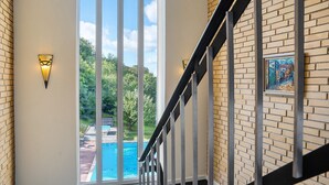 A staircase with a view of a swimming pool and greenery outside. - Hotel Hammersø - Adults Only (Allinge)