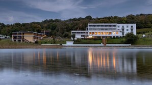 A modern building with a flat roof and multiple windows, situated near a body of water with reflections. - Hotel Hammersø - Adults Only (Allinge)
