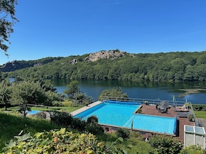 A swimming pool with a view of a lake and forested hills. - Hotel Hammersø - Adults Only (Allinge)