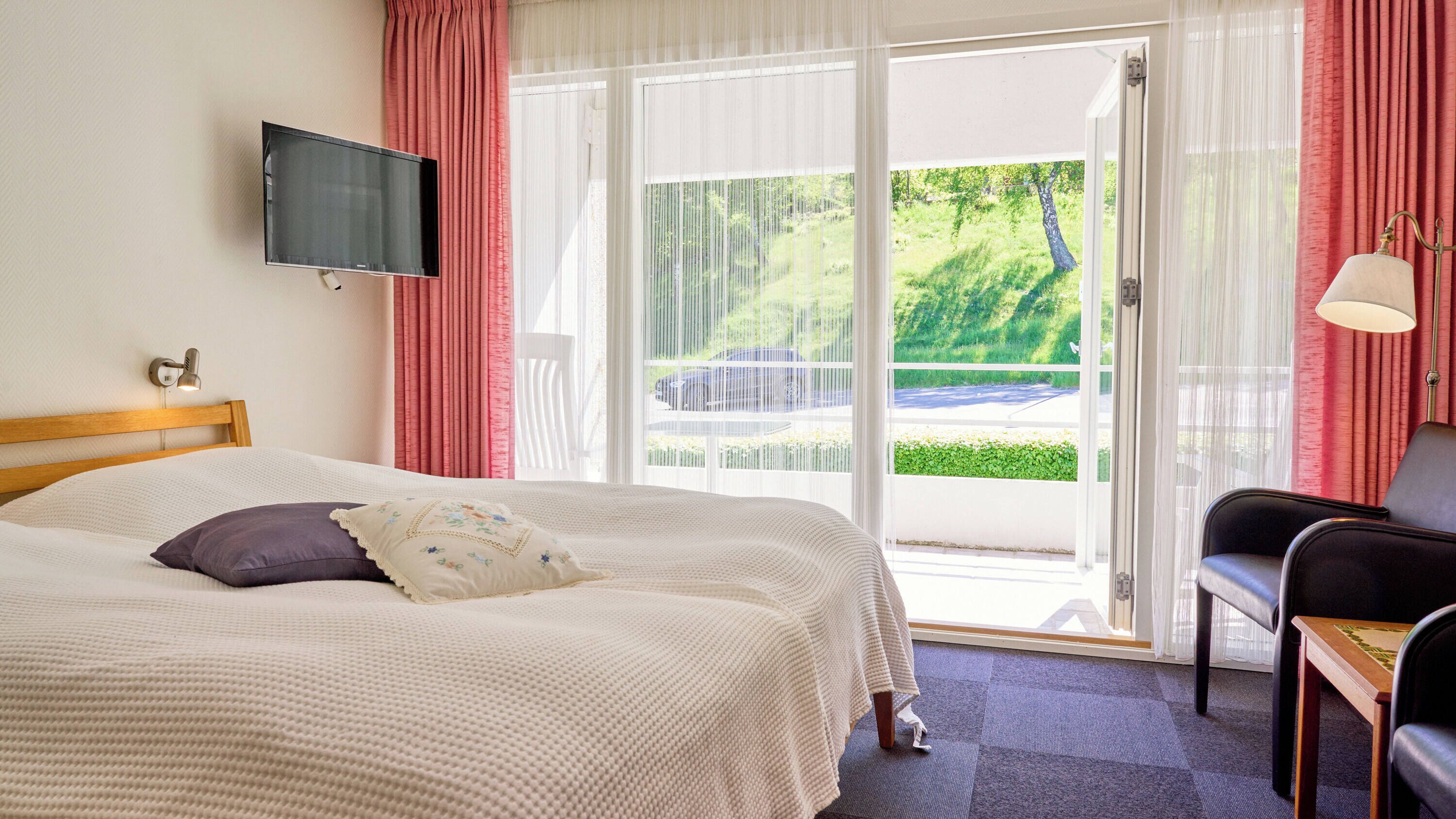 A hotel room with a bed, a TV mounted on the wall, a chair, and a table.