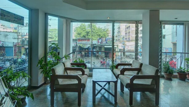 Un espacio interior amplio con ventanas grandes, varias sillas, una mesa y plantas en macetas.