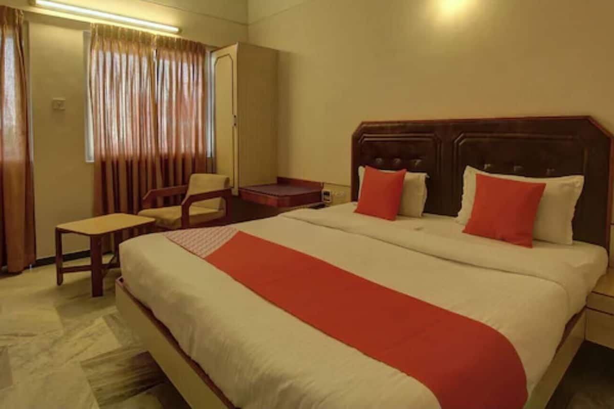 A hotel room with a large bed, a desk, a chair, and a wardrobe.