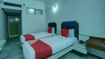 Habitación de hotel con dos camas, una mesita de noche, un teléfono y una puerta.