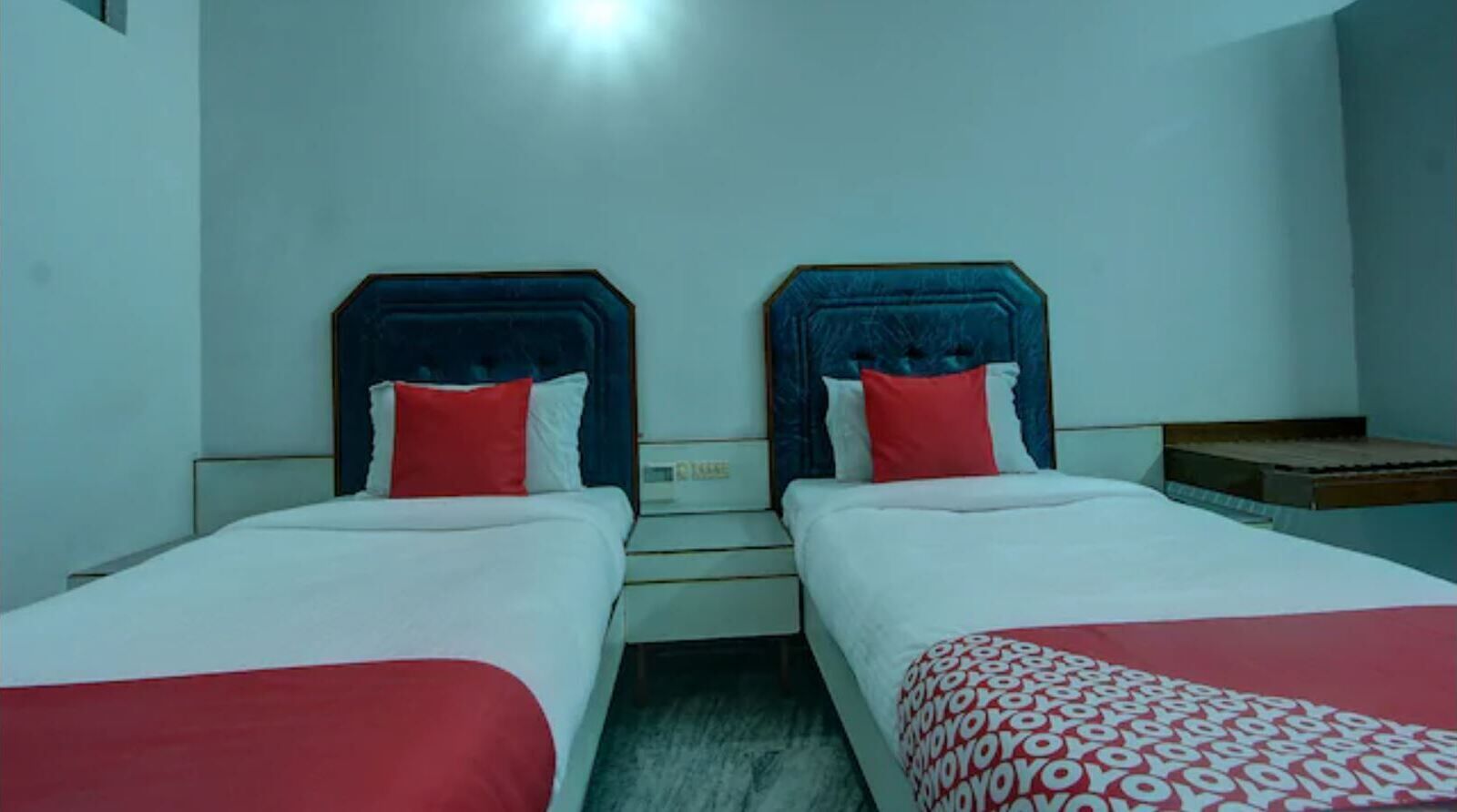 A hotel room with two single beds, each with a headboard and pillows.
