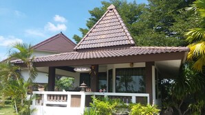 A two-story house with a tiled roof, a balcony, and a checkered pathway leading to the entrance. - Chortip Resort (Pak Phli)