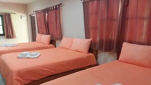 A hotel room with two beds, each with matching orange bedding and pillows, and a set of folded white towels on each bed. - Chortip Resort (Pak Phli)