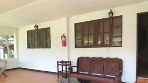 A room with a wooden bench, a table, and two windows with wooden frames. - Chortip Resort (Pak Phli)
