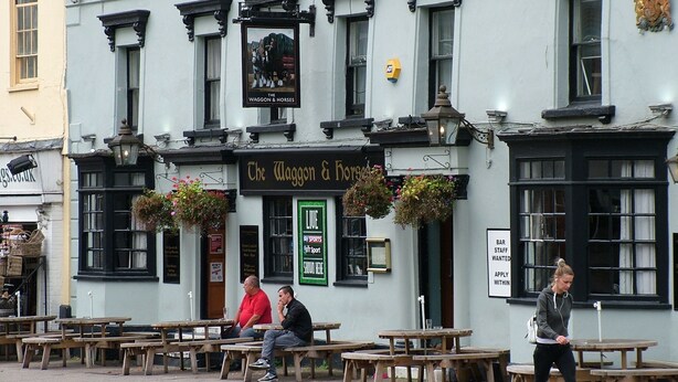 Eine Kneipe namens "Waggon & Horses Inn & Market House" mit Außenbestuhlung und hängenden Blumenkörben.