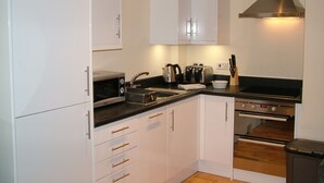 Eine moderne Küche mit weißen Schränken, einer Edelstahl-Dunstabzugshaube, einer Mikrowelle, einem Toaster und einem Spülbecken.