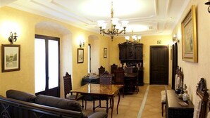 A dining area with a wooden table and chairs, a sofa, and a chandelier. - Hotel La Posada del Infante (La Puebla de los Infantes)