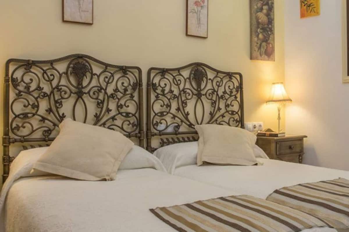 A double bed with a decorative headboard, two bedside tables, and a striped throw blanket.