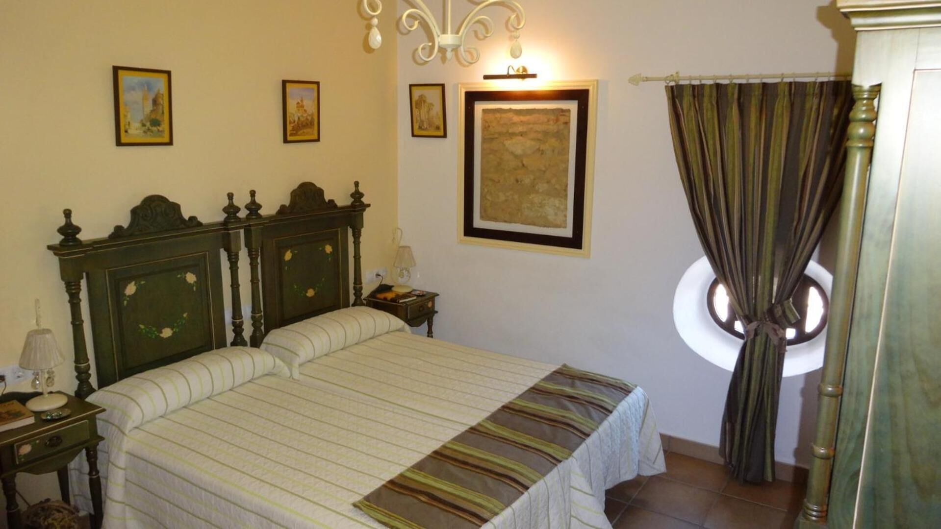 A bedroom with a large bed, a nightstand, a lamp, and a window with curtains.
