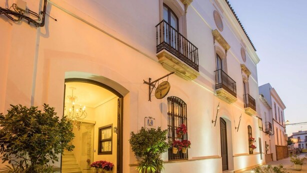 A traditional building with a well-lit entrance, potted plants, and a sign indicating a restaurant. - Hotel La Posada del Infante (La Puebla de los Infantes)