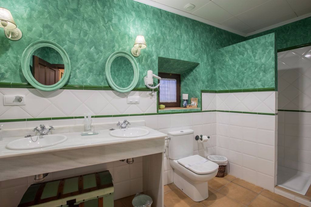 A bathroom with two sinks, a toilet, and a shower.