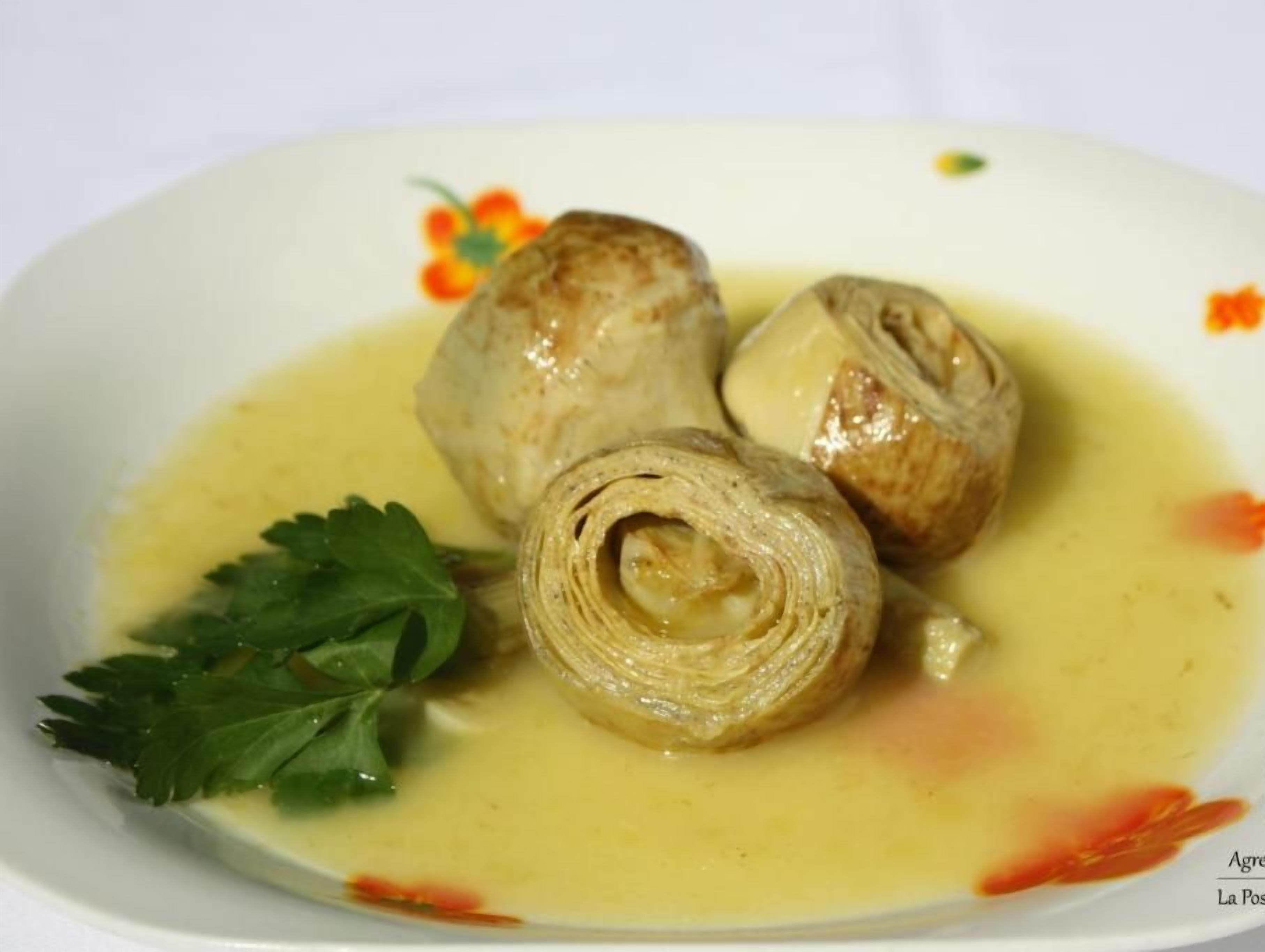 Un piatto con tre involtini in salsa cremosa, guarnito da una foglia, su un piatto bianco con decorazioni floreali.