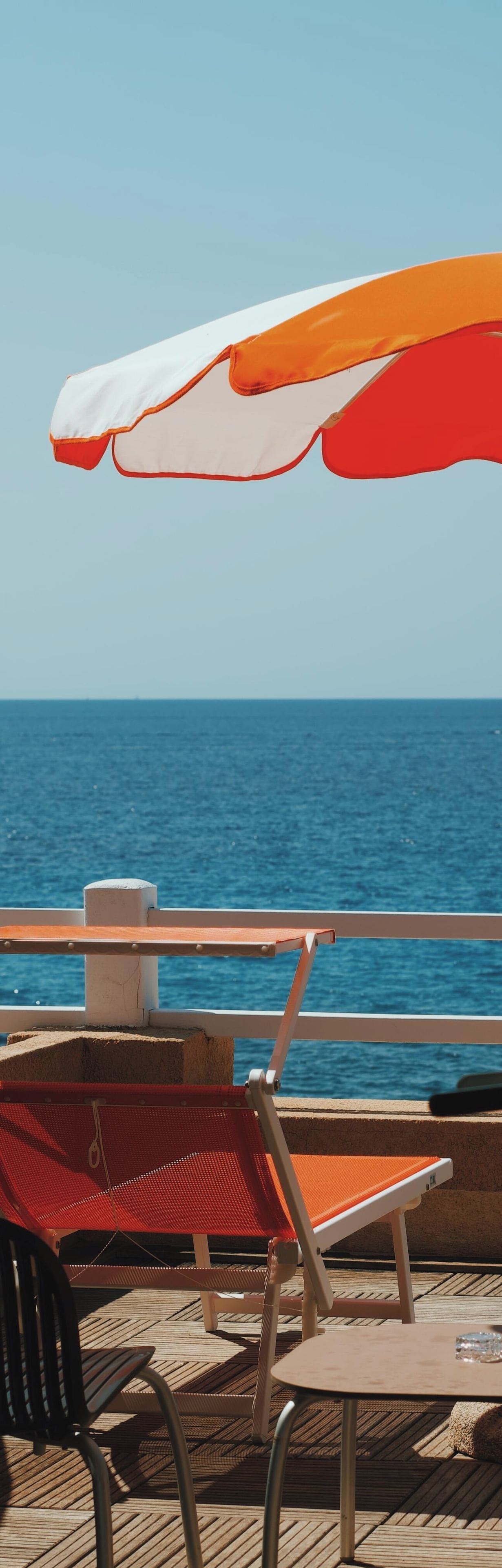 A deck with outdoor seating and a view of the sea.