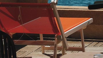 A deck with outdoor seating and a view of the sea.