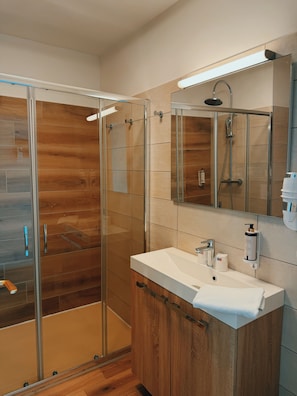 Ein modernes Badezimmer mit einer Duschkabine aus Glas, einem Holzbadezimmermöbel und einem großen Spiegel.
