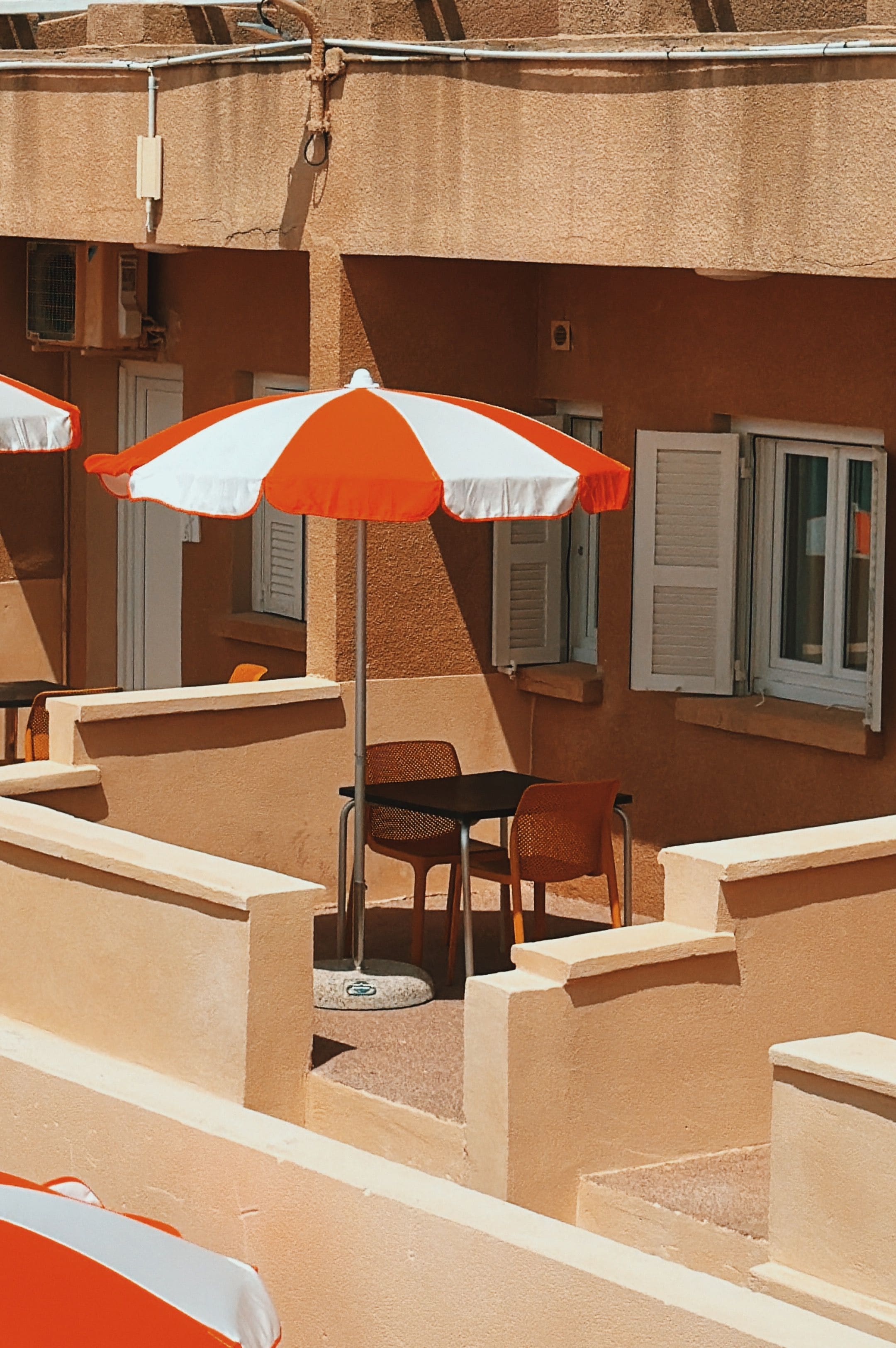Una terraza con mobiliario exterior, incluyendo sillas y mesas, y una zona cubierta con sombrillas.