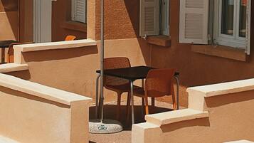Una terraza con mobiliario exterior, incluyendo sillas y mesas, y una zona cubierta con sombrillas.