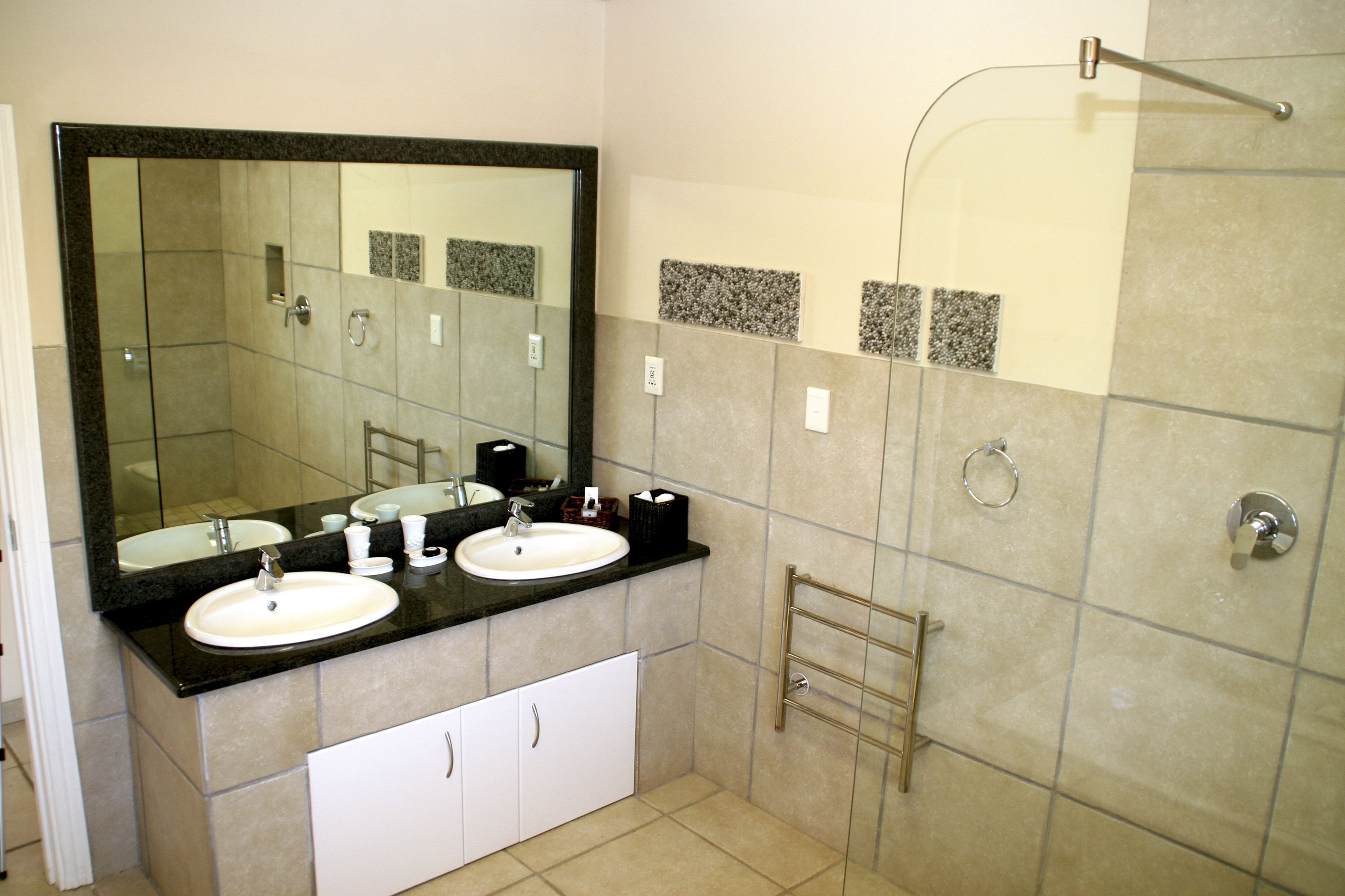 A bathroom with two sinks, a large mirror, and a shower area.