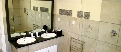 A bathroom with two sinks, a large mirror, and a shower area.