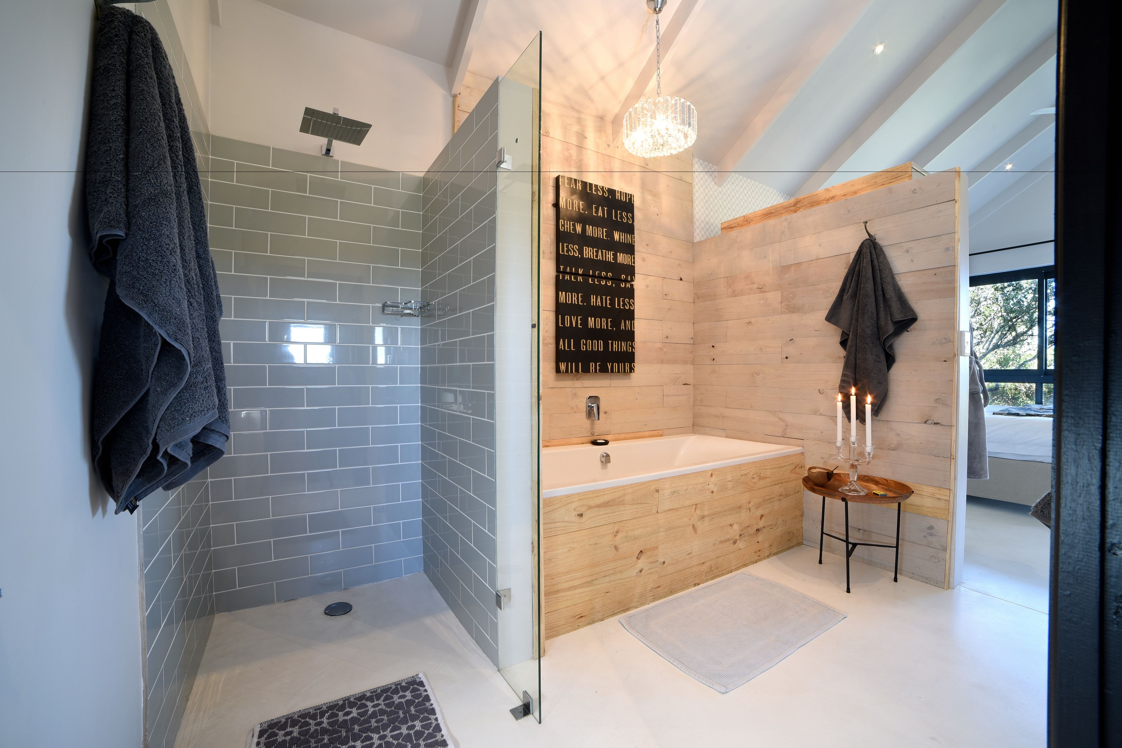 Un bagno moderno con cabina doccia in vetro, mobile lavabo in legno e un grande specchio con citazioni motivazionali.