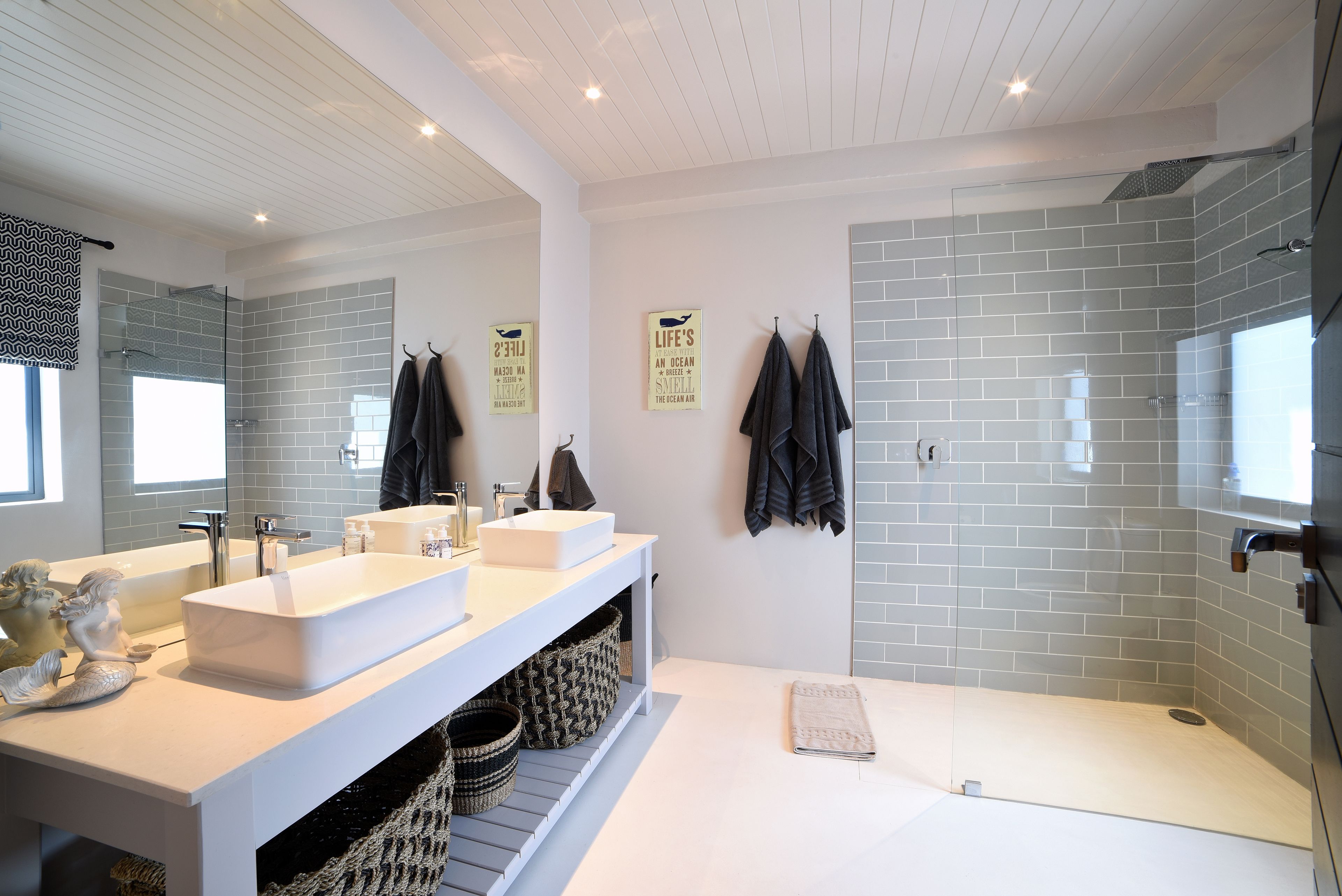 Un bagno moderno con due lavabi, cabina doccia in vetro e uno specchio grande.