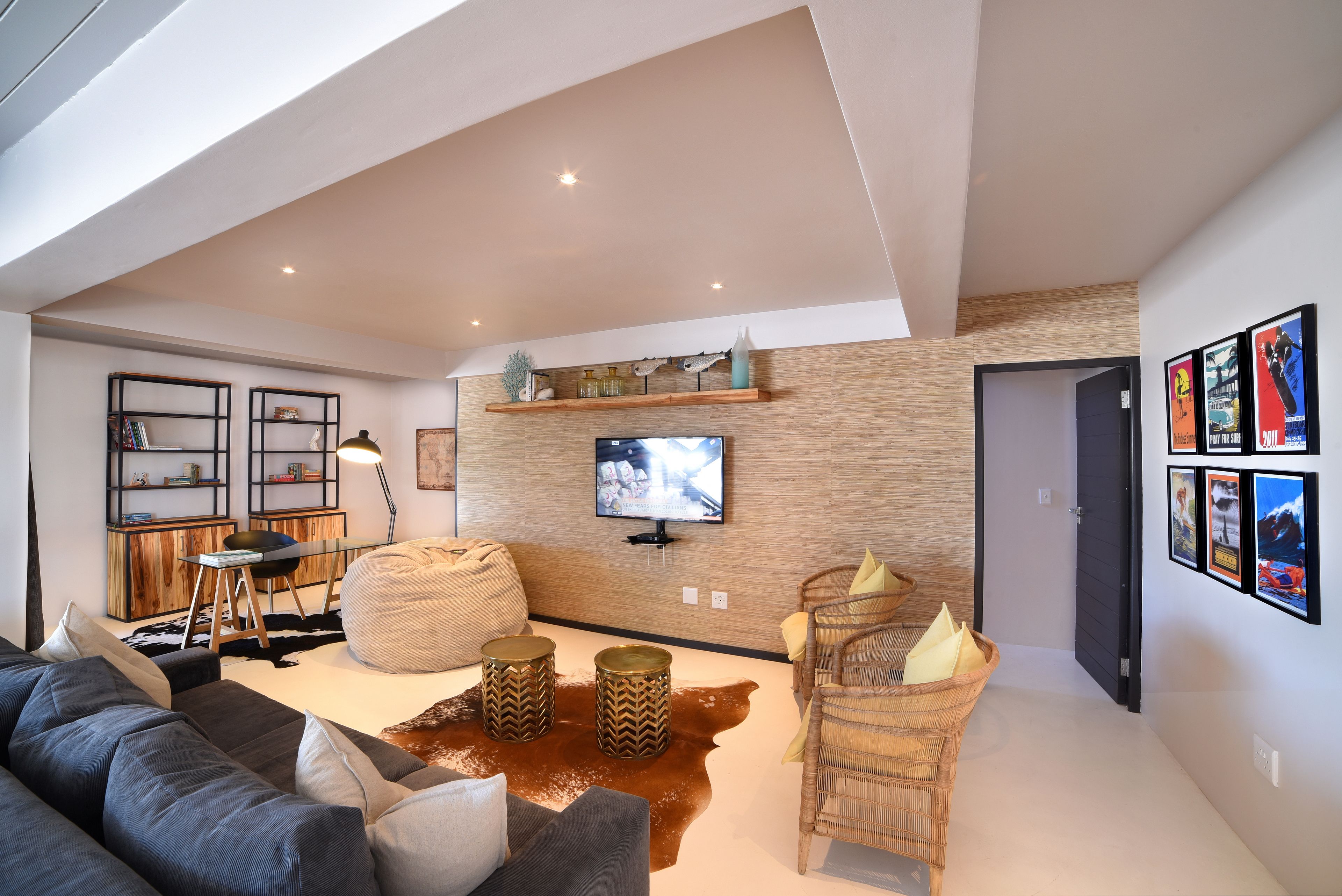 A modern living room with a sofa, a television, and a wall-mounted shelf.