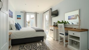 A bedroom with a bed, desk, chair, and a TV on the wall. - BlueSky Arniston Boutique Guesthouse (Arniston)