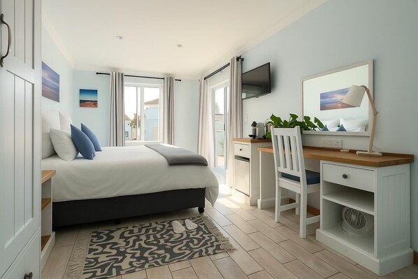 A bedroom with a bed, desk, chair, and a TV on the wall. - BlueSky Arniston Boutique Guesthouse (Arniston)