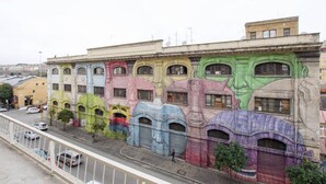 A building with colorful murals on its facade, featuring various architectural elements and windows. - Affittacamere Il Porto (Rome)