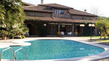A house with a swimming pool, a covered patio, and a stone facade.