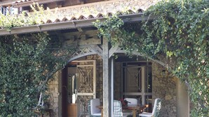 An outdoor patio with stone walls, a wooden pergola, and green chairs. - All'ombra del palmeto (Taranto)