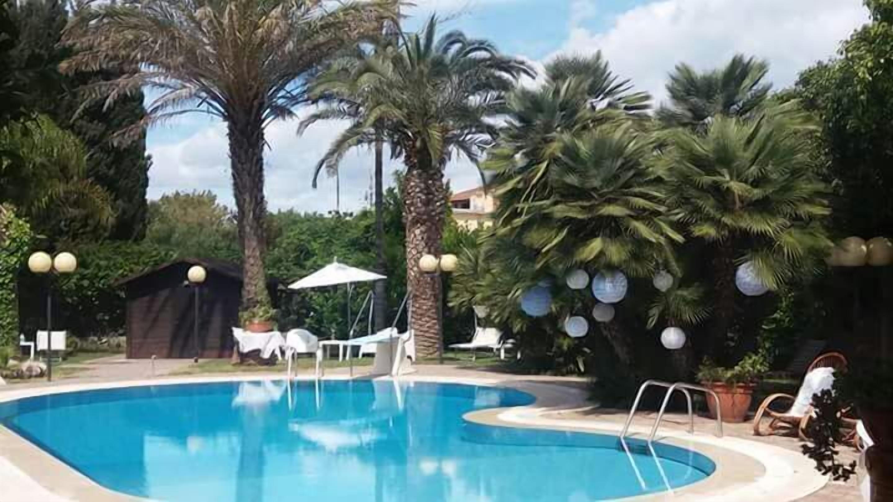 A swimming pool surrounded by palm trees and lounge chairs.