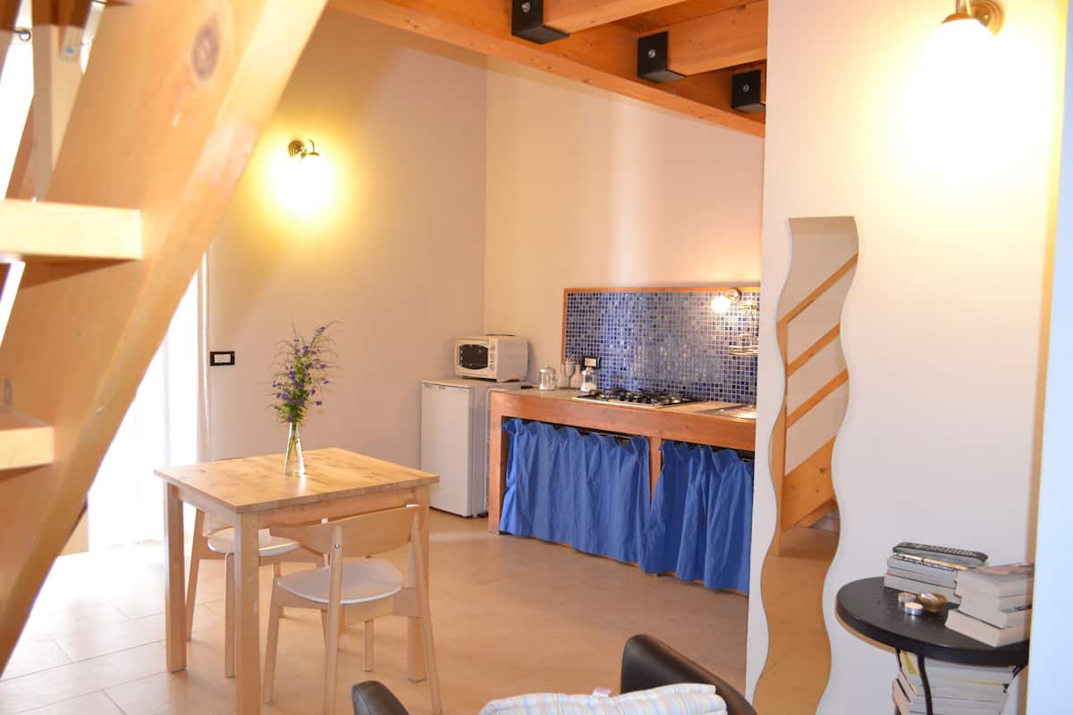 A compact kitchen with a dining area, a small refrigerator, and a microwave.