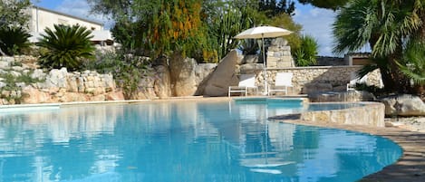 Una piscina al aire libre de temporada, sombrillas