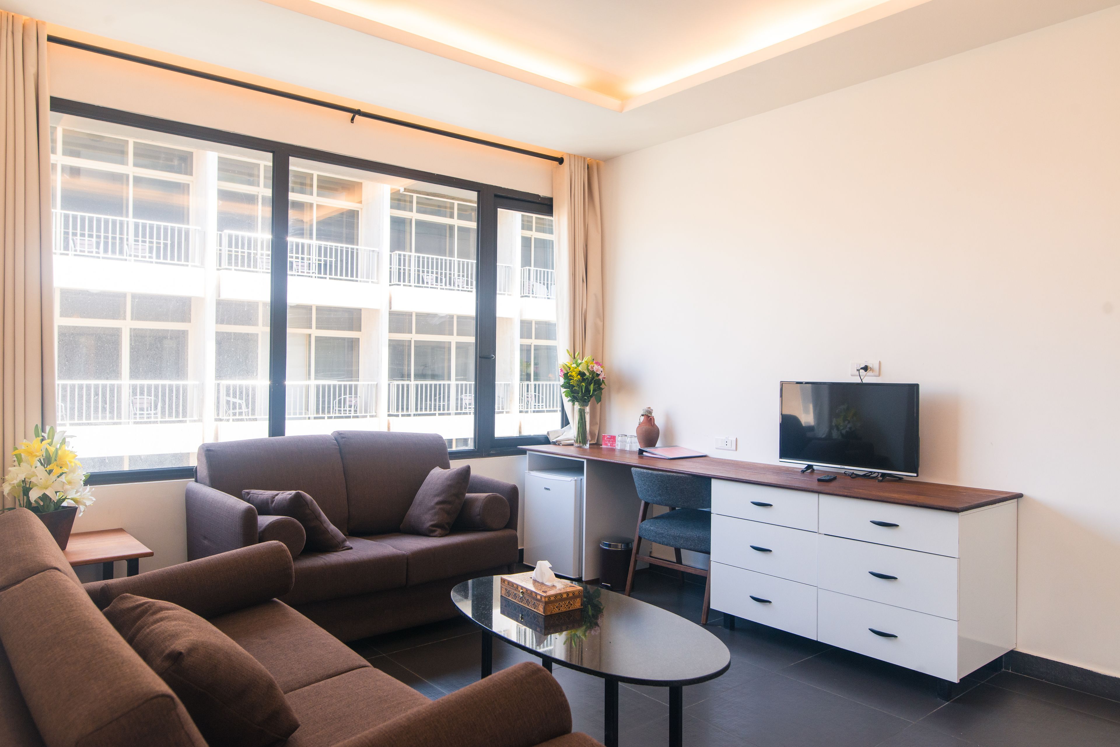 A modern living room with a sofa, coffee table, and a TV on a wooden cabinet.