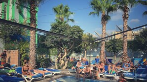 A swimming pool area with lounge chairs and palm trees. - Hamra Urban Gardens (Beirut)