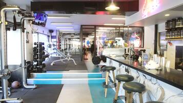 Une salle de sport équipée de matériel d’exercice, un espace bar et un panneau lumineux au néon.