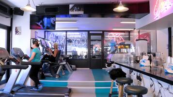 A gym with treadmills, exercise bikes, and a bar area with stools.