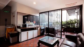 A modern kitchen with a microwave, sink, and cabinets, a glass coffee table, and a sofa.
