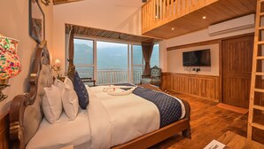 Un dormitorio espacioso con una cama grande, techo de madera, un balcón con vistas y un televisor en la pared.
