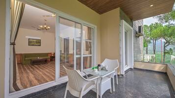 Un balcon avec une table et des chaises en verre, une vue sur l’intérieur et un plafond en bois.